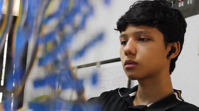 Portrait of a Latino teenager focused while working on building a robot at a table in a club in Neiva, Huila, Colombia. Concept of education and technology
