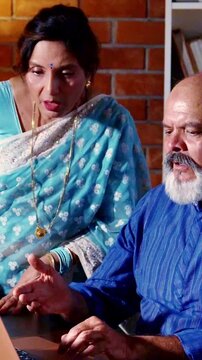 Asian Indian elderly couple feeling upset and emotional after receiving heartbreaking news late at night in their home