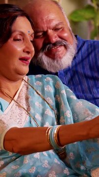 Asian Indian senior couple happily posing together for a selfie in their modern home, capturing a joyful moment filled with love and laughter during their retirement