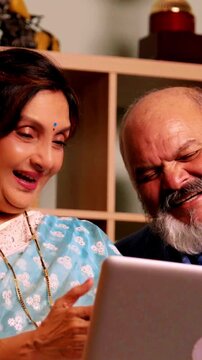 Joyful Indian Asian senior couple, happily retired, enjoying talking to their family on  a video call with love