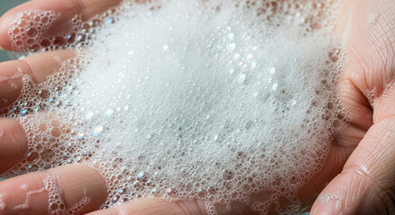 Fototapeta premium Close-up of lathering soap bubbles on a human hand, hygiene and cleanliness concept