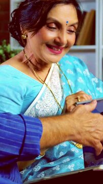 Asian Indian retired couple enjoying old memories together as they look through a photo album on yellow couch at their beautiful home