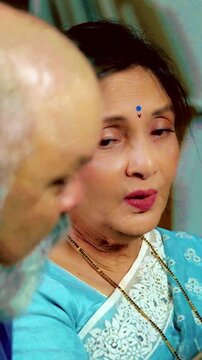 Retired Indian couple enjoys a joyful and relaxing time at home, as the husband plays the guitar and the wife sings, creating a heartwarming moment filled with music and love