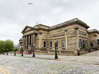 Obraz premium Historic neoclassical stone building with columns at Walker Art Gallery in Liverpool, UK overlooking empty cobblestone street under an overcast sky