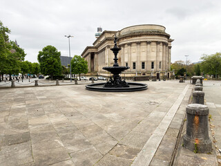 Obraz premium Neoclassical building and ornamental fountain on a wide paved plaza in Liverpool, UK under an overcast sky