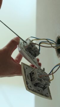 Vertical video Professional electrician working on a home electrical system. Close up man installing a wall socket at new apartment or house.