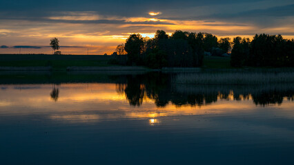 Naklejka premium beautiful sunset, sunrise landscape by the lake, reflections on the surface of the calm lake water, bright colors,