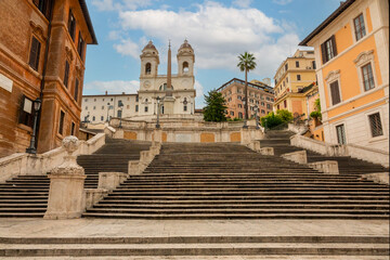 Obraz premium Piazza di Spagna - Spanish Steps - in the morning in Rome, Italy with view of the Trinità dei Monti church on a sunny day with blue sky and white clouds.&nbsp;