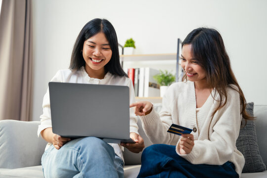 Two young Asian women used a laptop computer to shopping online and paid by credit card.