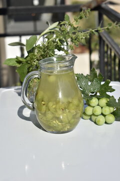 Homemade Verjuice Drink in Glass Pitcher with Fresh Green Grapes on White Garden Table, Refreshing Summer Beverage