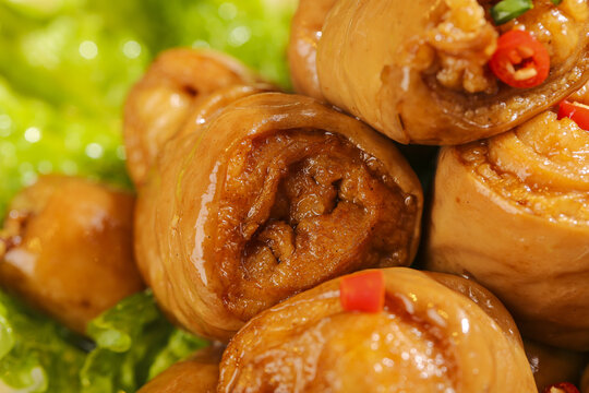 Classic Chinese braised pork intestine rolls with chili peppers and herbs close-up food photography