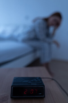 Clock shows 2 am while woman sits on bed