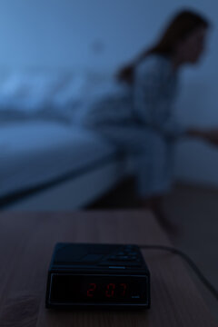 Clock shows 2 am while woman sits on bed