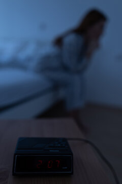 Clock shows 2 am while woman sits on bed