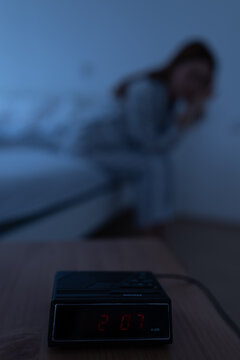 Clock shows 2 am while woman sits on bed