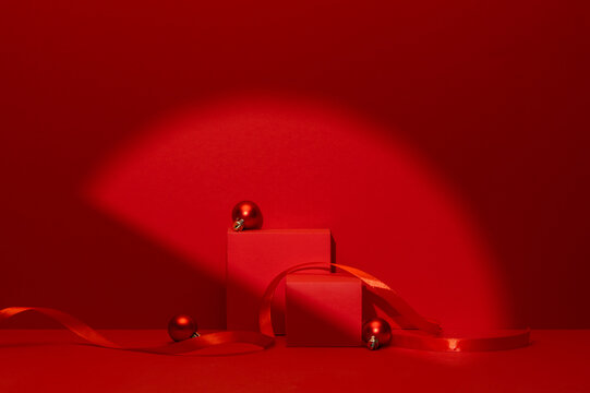 Red Christmas Product Display Podiums with Ornament Balls and Ribbon Under Circular Spotlight on Dark Red Background