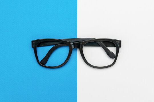 Minimalist Black Glasses Displayed on Split Blue and White Background Highlighting Symmetry and Contrast