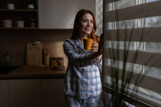Woman gazes out window at dawn