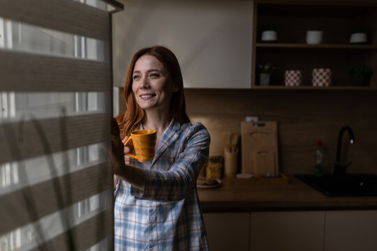 Woman gazes out window at dawn
