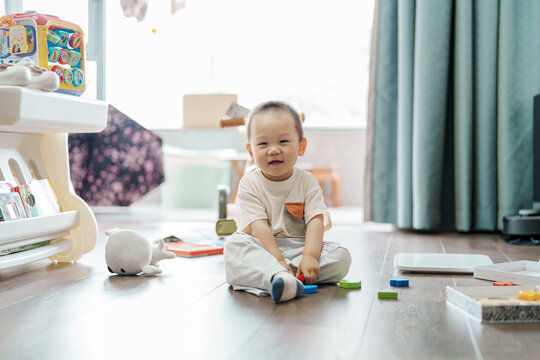 Little boy playing with colorful blocks on living room floor