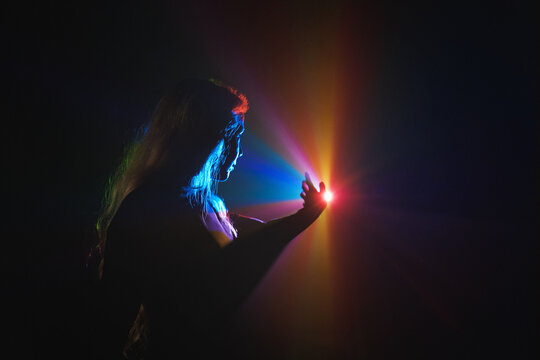 Cool portrait young girl who stretches her finger towards the rainbow neon rays. Concept - Discover the modern digital AI world.