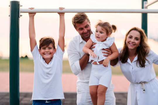 Happy Family Playing Together at Seaside Park Playground Near Marina on a Summer Evening