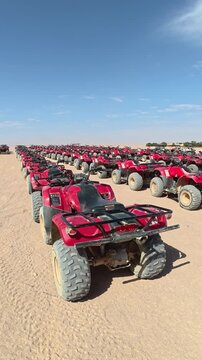 Aerial and ground level cinematic view of dozens of red quad bikes lined up in the desert, ready for an off road safari adventure. 