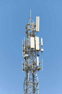 Cellular telecommunication tower with mobile network antennas against clear blue sky. Transceiver base station for high-speed 4G LTE and 5G wireless internet connection and signal transmission.