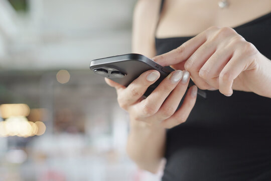 woman holds smart phone in her hands and scrolls through the news feed. Close up of hand uses mobile. point finger on screen, texting text message.