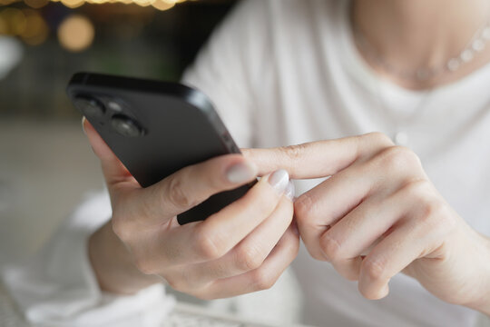 woman holds smart phone in her hands and scrolls through the news feed. Close up of hand uses mobile. point finger on screen, texting text message.