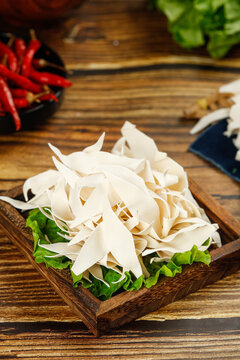 Handmade Wide Rice Noodle Slices with Green Lettuce on Wooden Board - Asian Cooking Ingredients