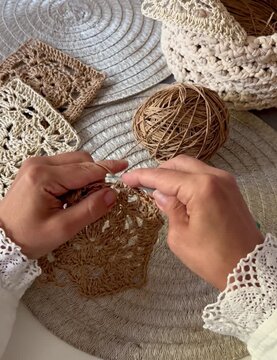 hands crocheting a raffia granny square with lace cuffs ,handmade basket and slow living craft 