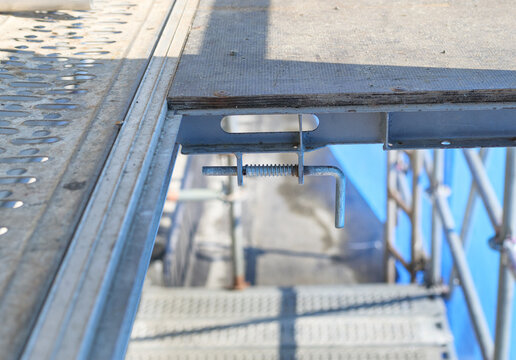 Open scaffolding door lock mechanism. Close up of open staircase hatch in scaffolding tower. Construction site safety and security. Prevent work related accident concept. Selective focus.
