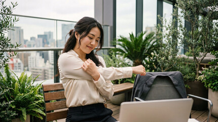 Fototapeta premium Young business woman stretching arms during break on office balcony overlooking cityscape, promoting wellness and work-life balance