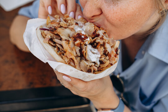 Woman Eating Grilled Chicken Shawarma Wrap With Yogurt Sauce Close up Street Food Bite , Sandwich Gyro or   Doner Kebab Outdoors