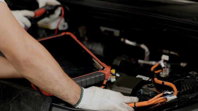 Professional Engineer checking EV car problem with OBD Monitor system equipment tool in EV Garage auto service