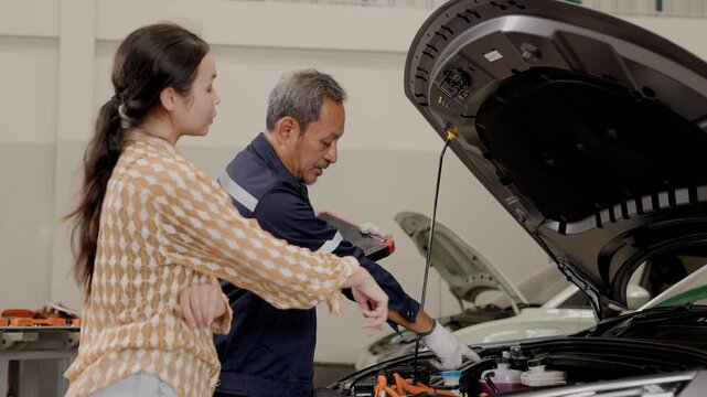 Professional Asian senior mature EV Car service male worker talking discuss with woman customer EV car owner for explaining problem for service process