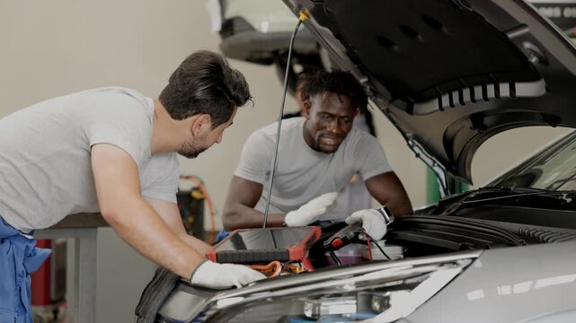 EV Car engineer team working service maintenance Electric cable in front of EV car hood checking replacing or installation