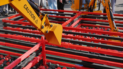Excavator bucket picking up red and black balls during sports day