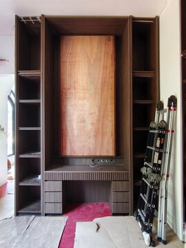 Modern minimalist custom wood cabinet desk with drawers under installation process in a building interior