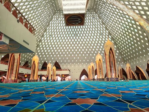 Bandung, Indonesia - July 8, 2026: Low angle view of the main prayer area of Al Jabbar Grand Mosque with expansive blue carpet patterned with islamic geometry