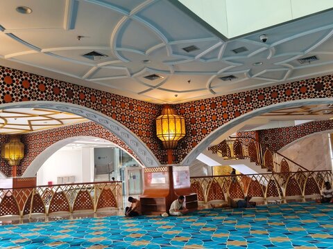 Bandung, Indonesia - July 8, 2026: Visitors resting on the corridor floor of Al Jabbar Grand Mosque adorned with arches decorated with mosaic ornaments