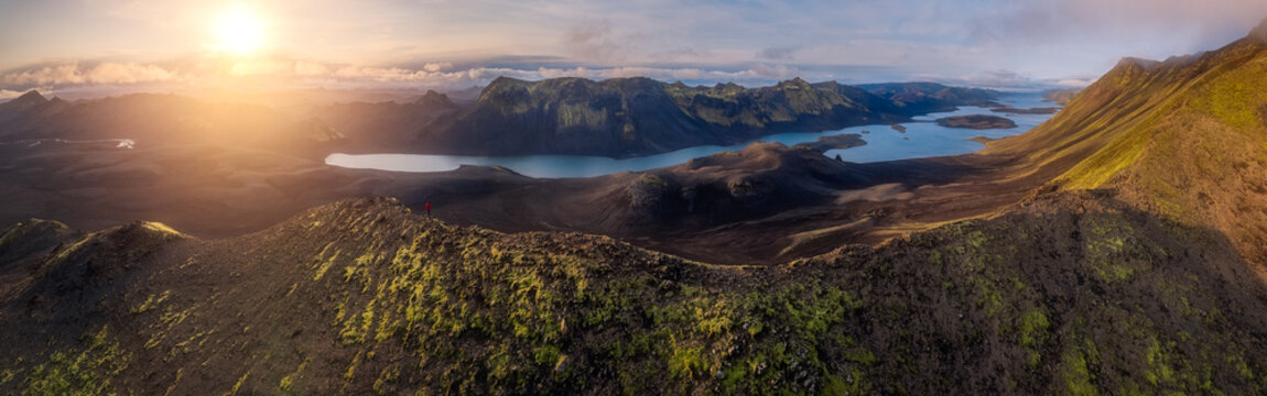 Solitary explorer above a remote wilderness landscape
