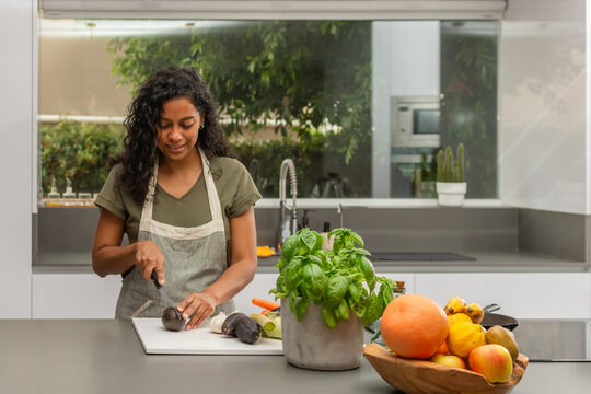 Smiling woman preparing fresh avocado in bright modern kitchen