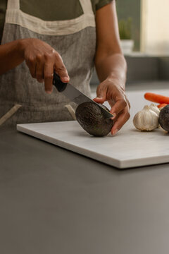 Close up of cutting avocado on wooden cutting board in modern kitchen