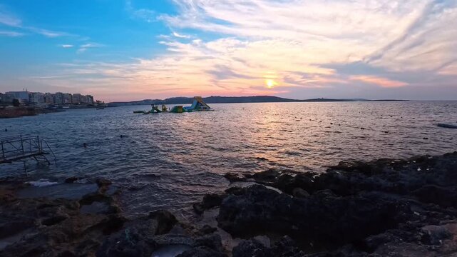 People Jumping Into the Sea at Sunset From Coastal Pier, Bugibba Beach, Malta - STEADY VIDEO - NO AUDIO