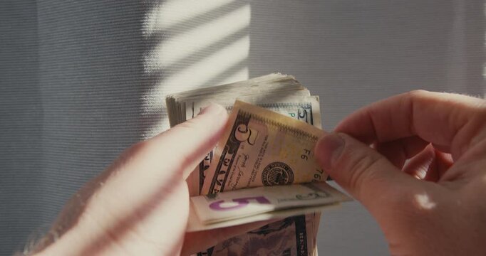 Hands counting a thick stack of dollar bills