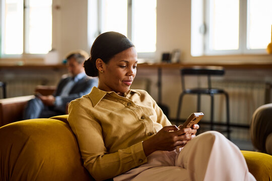 Businesswoman uses a mobile phone while sitting comfortably