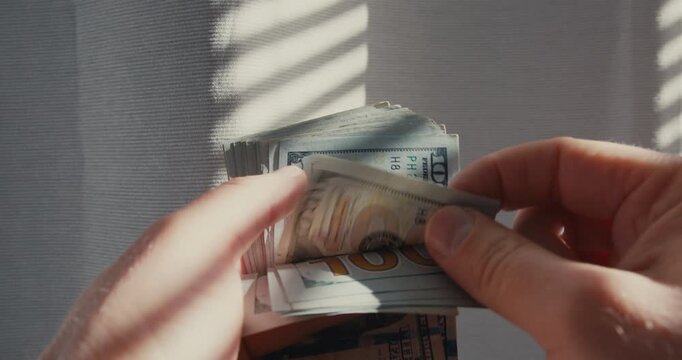 Hands counting a stack of hundred dollar bills