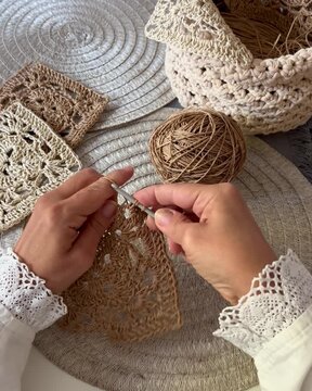 Wuman&rsquo;s hands with lace cuffs crocheting a raffia granny square , vintage style, slow living 